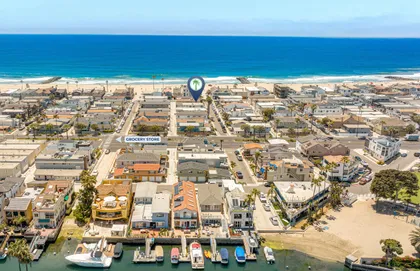 Sweeping aerial perspective of the harbor and beachfront neighborhood, showcasing the home’s prime location near the coast