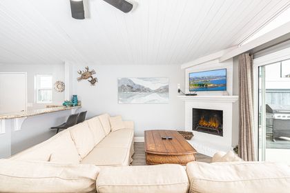 The living area includes sofa, cable TV, dining table with seating for 6, and kitchen beyond.