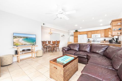 Sliding doors from the front patio open into the main living area, with large leather sectional, streaming TV, and kitchen and dining beyond.