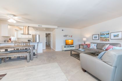 Vantage point from the unit's entry area toward living room and TV. Carpeting throughout this upper unit.