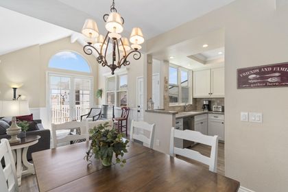 Vantage point from dining table and seating toward kitchen, living room and TV. Wood-look tile flooring throughout all living spaces.