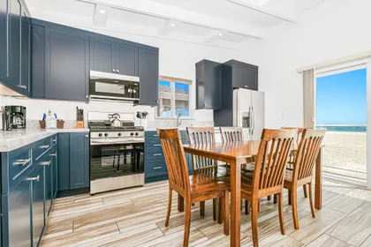 The kitchen stretched along the wall beyond the dining area and is stocked with dishes, utensils, cookware, bakeware, and large and small appliances.