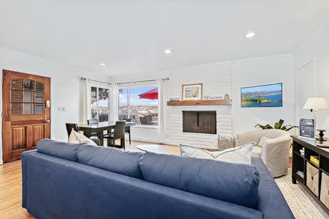 The living and dining area are framed by bay-view windows, creating a relaxed yet refined space for coastal living
