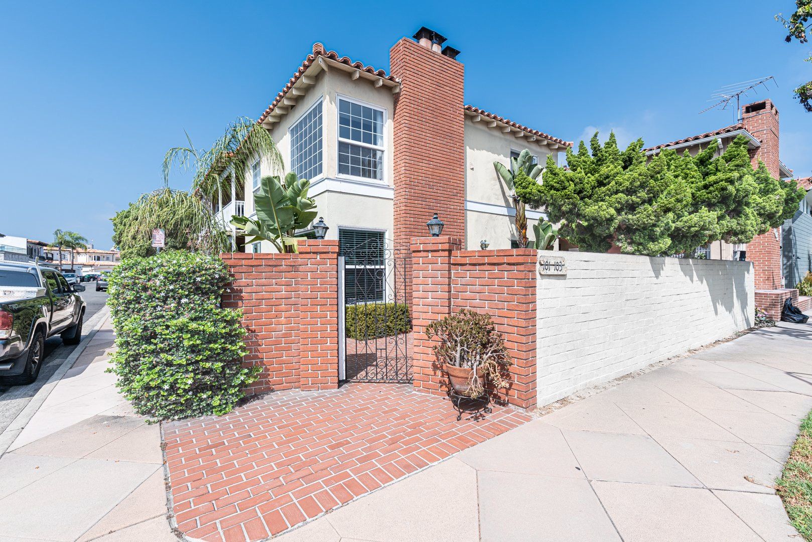 Charming Newport Beach home featuring a classic brick façade, lush landscaping, and a sunny front patio just moments from the coast