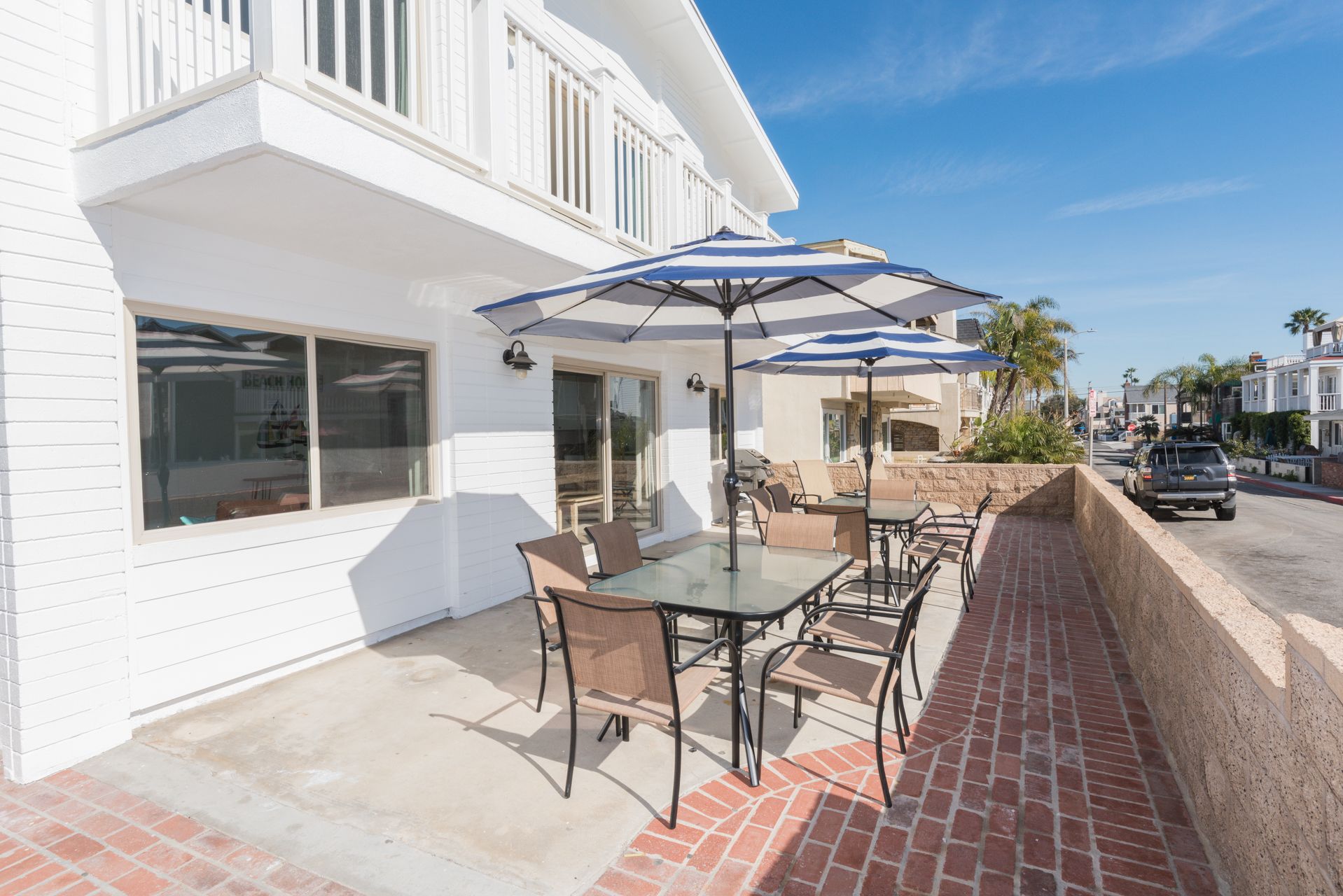 The front patio area includes outdoor dining table with seating, market umbrellas, and propane gas grill for sunset cookouts.