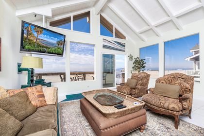 The main living area includes sofa seating, cable TV, fireplace, large windows, and a sliding glass door that leads to the front patio.