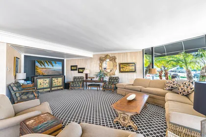 Pictured here is the main living area, with large sectional, additional seating, back-to-back gas fireplace, TV and sound system, and sliding doors out to the front patio.
