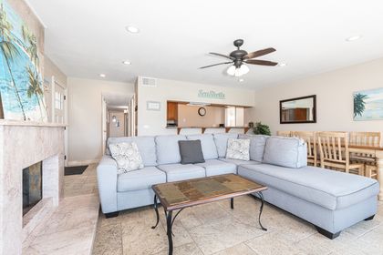 Beachy interior, with large couch, TV, and direct access to the front patio.