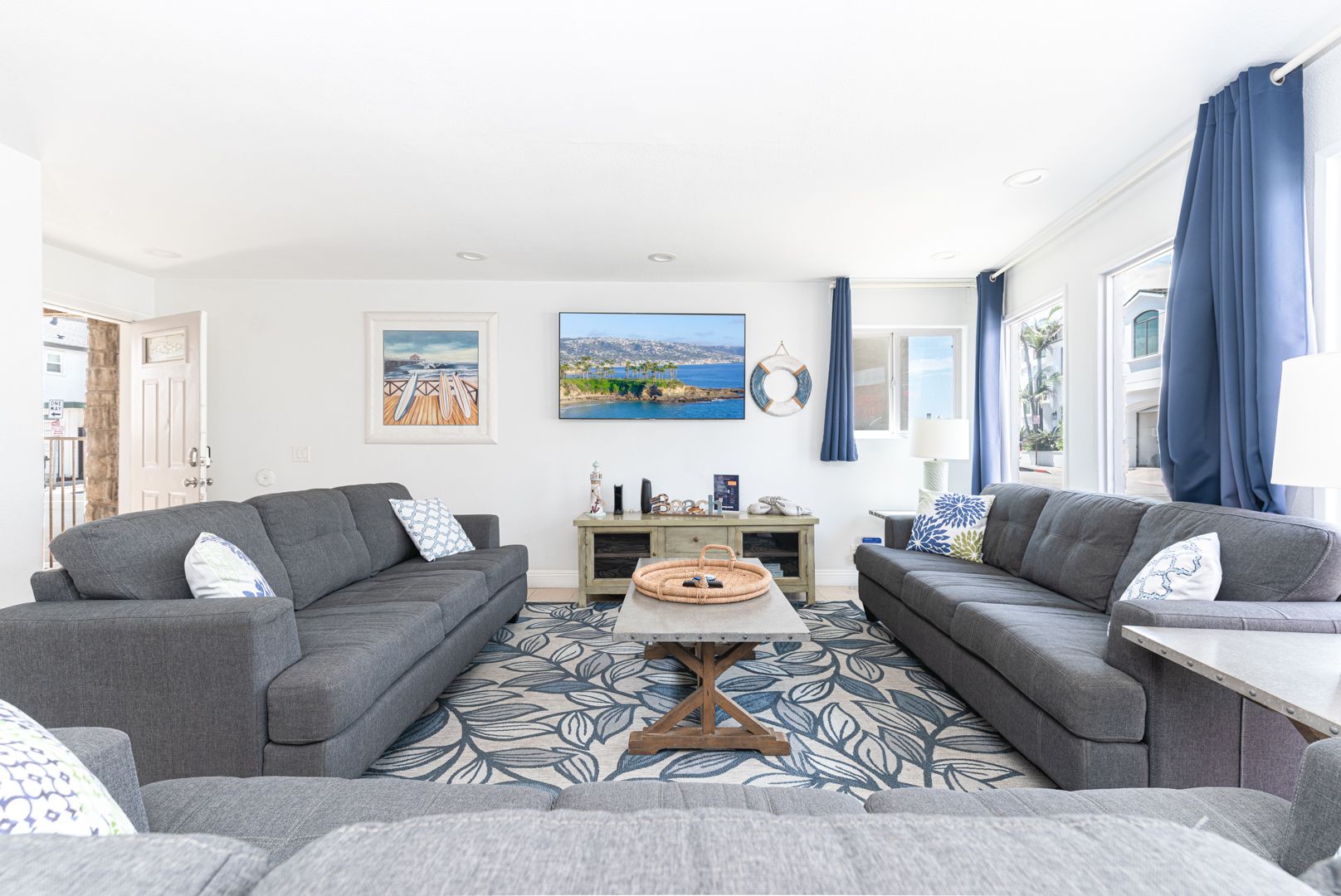 Open up the front door into the main living area, which includes a sofa/loveseat set, side seating, cable TV, and a sliding glass door that opens to expansive front ocean view patio.