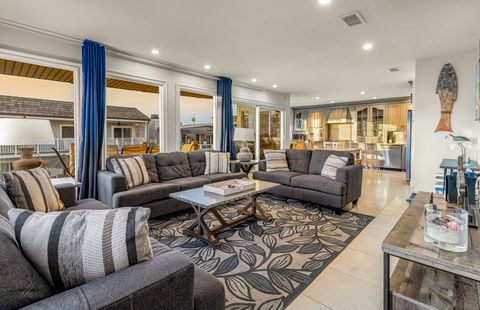 The serene and airy living area includes sofa/loveseat set, side seating, cable TV, and sliding glass door that opens to spacious ocean view deck