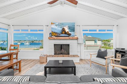 The living room is beautifully framed by expansive bay-view windows, filling the space with natural light and coastal ambiance