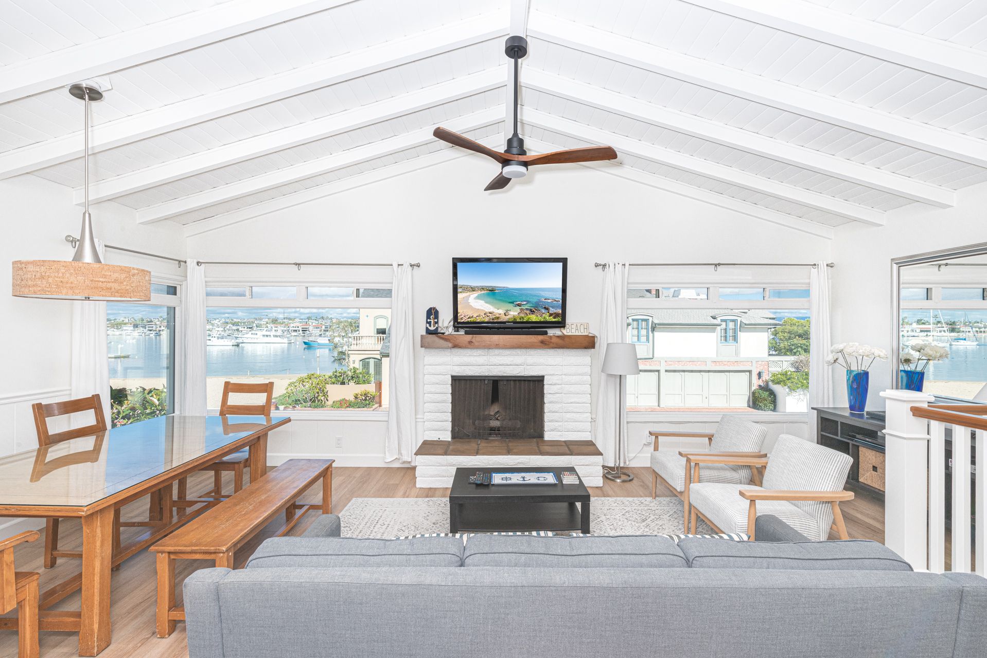 The living room is beautifully framed by expansive bay-view windows, filling the space with natural light and coastal ambiance