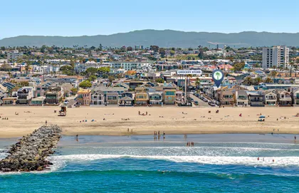 Drone perspective highlighting the home’s prime placement with easy access to soft sand, surf, and the vibrant Newport shoreline