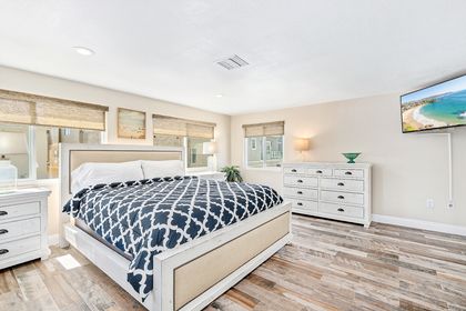 The primary bedroom includes a king bed, TV, en suite bathroom, and peek-a-boo ocean view.