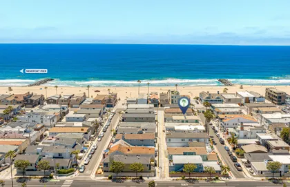 Aerial view of the neighborhood just steps from the sand, with the sparkling Pacific Ocean stretching across the horizon