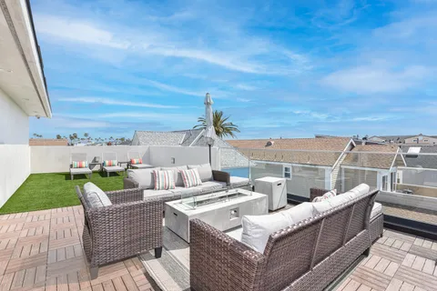 Rooftop deck of this modern three-level vacation home. Ample seating and gas fire pit make this THE hangout spot after a day at the beach.