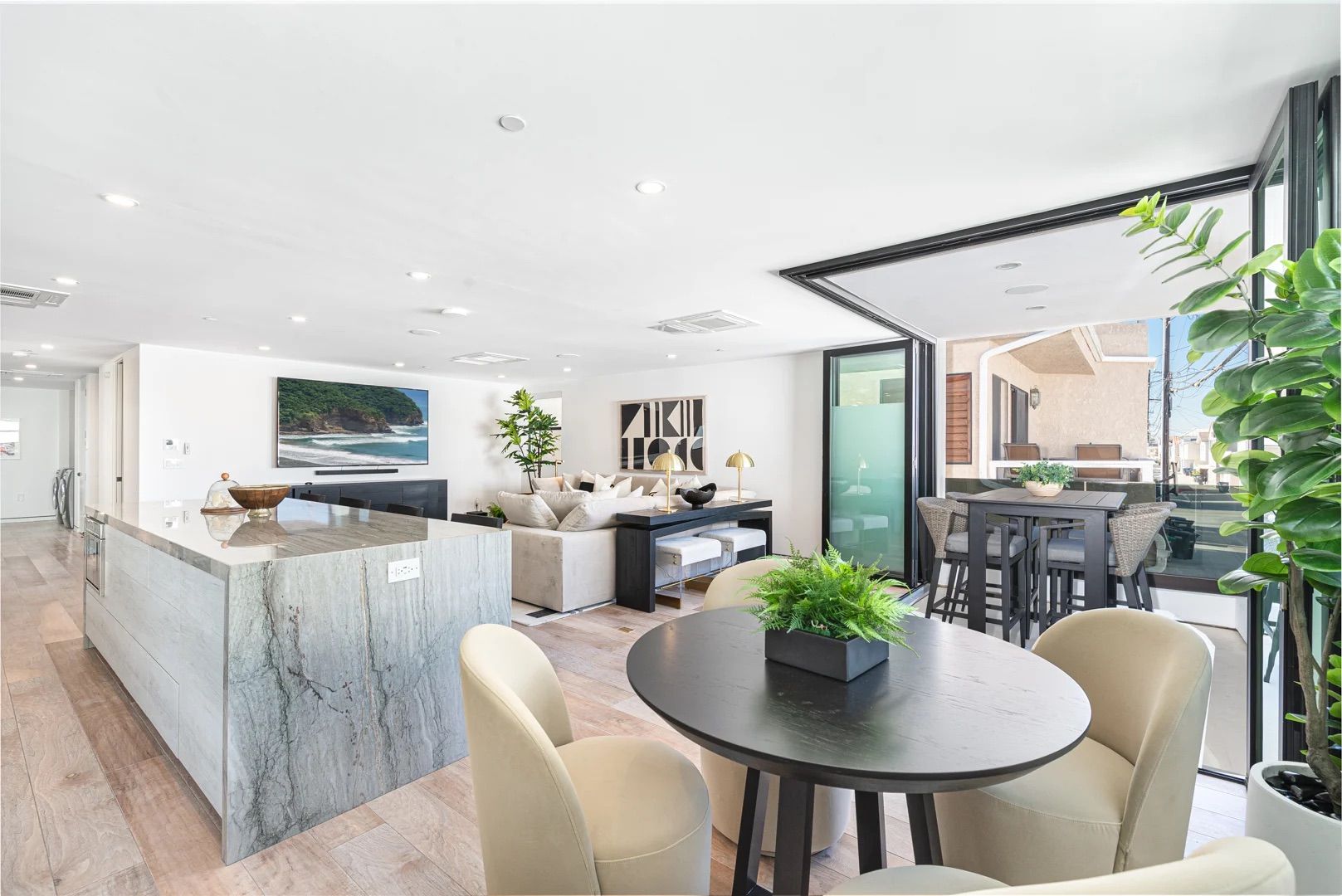 Open-concept kitchen, dining, and living space featuring designer finishes and sliding door leading to a covered balcony