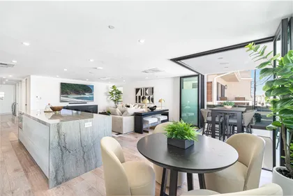 Open-concept kitchen, dining, and living space featuring designer finishes and sliding door leading to a covered balcony
