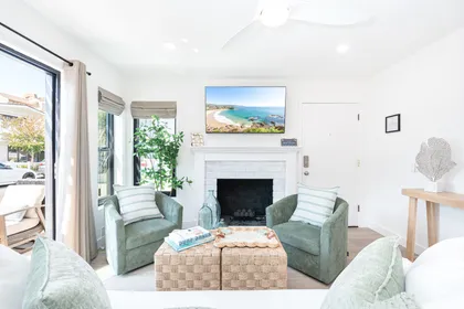 Relax in this bright, beach-inspired living space featuring plush seating, a charming fireplace, and a flat-screen TV