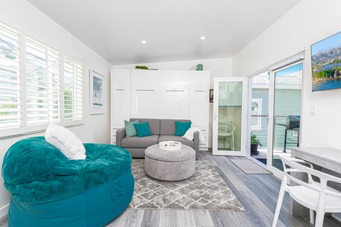 The main living area includes a queen Murphy bed, desk area, TV, and easy access to the sunny outdoor deck.