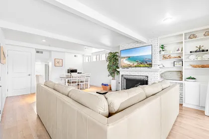 The living area is bright and open, for easy breezy hangouts. It includes a large sofa, TV, and sliding doors out to front patio.