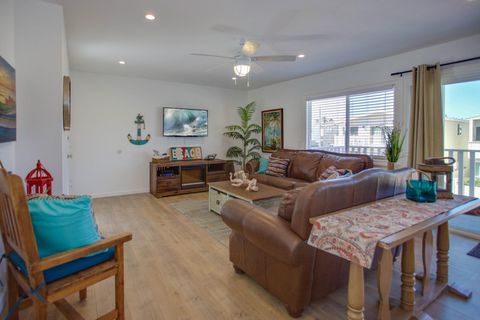 Vantage point from dining table and seating toward kitchen, living room and TV. Wood-look laminate flooring throughout.