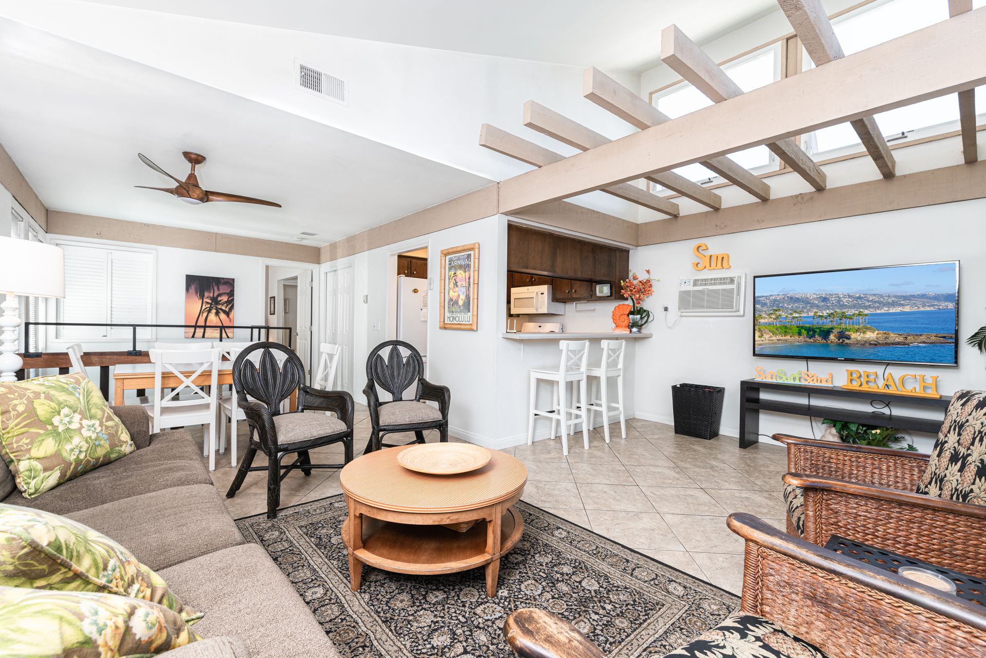 Stairs lead you to the main upper level, with sofa, side seating, cable TV, and kitchen beyond.