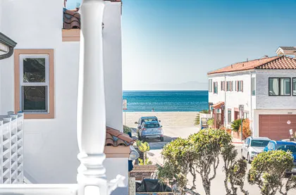 Peek of the Pacific framed by charming architecture and swaying trees